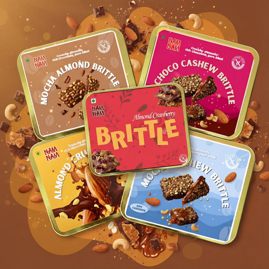 Five colorful tins of NAM NAM brittle with different flavor names on a brown background.